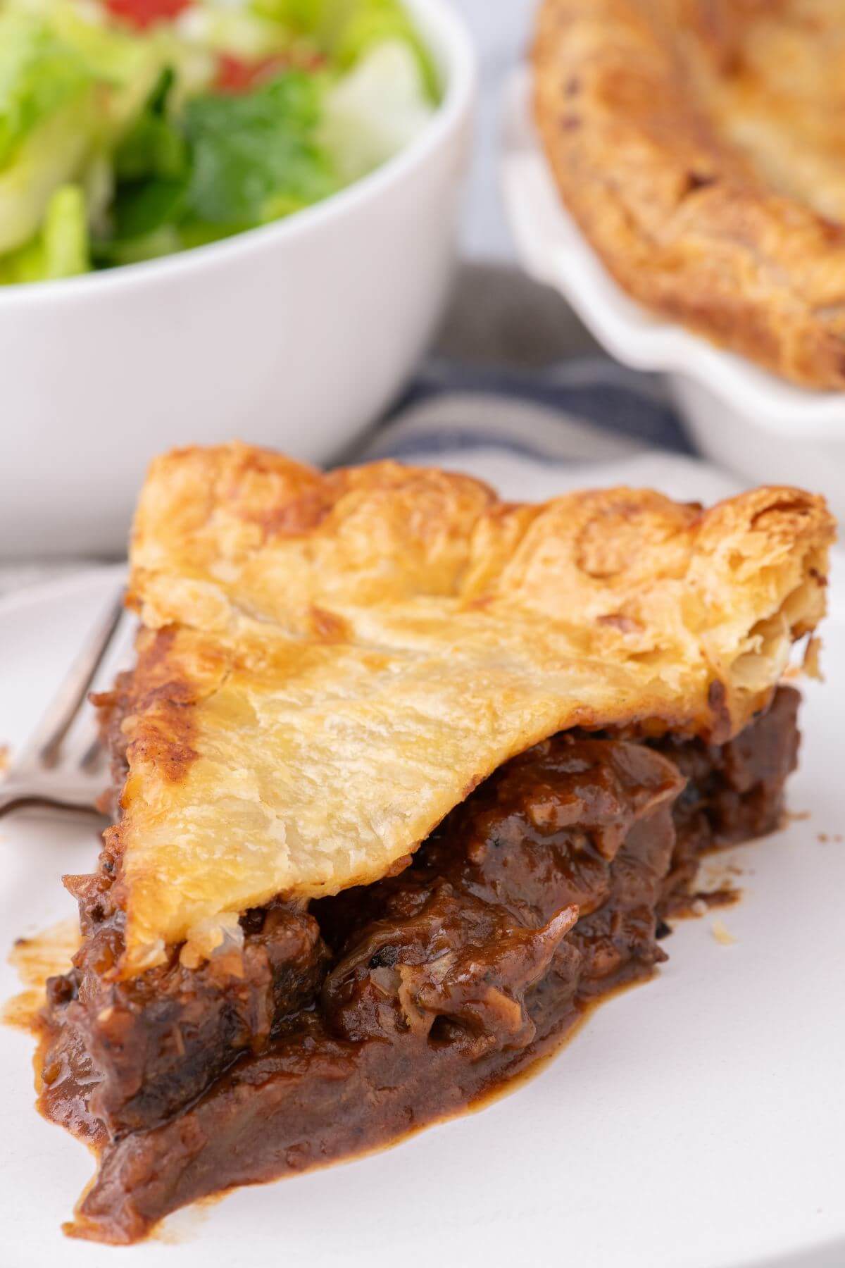 A piece of Irish steak pie shows a thick, hearty filling of steak in a rich ale gravy.