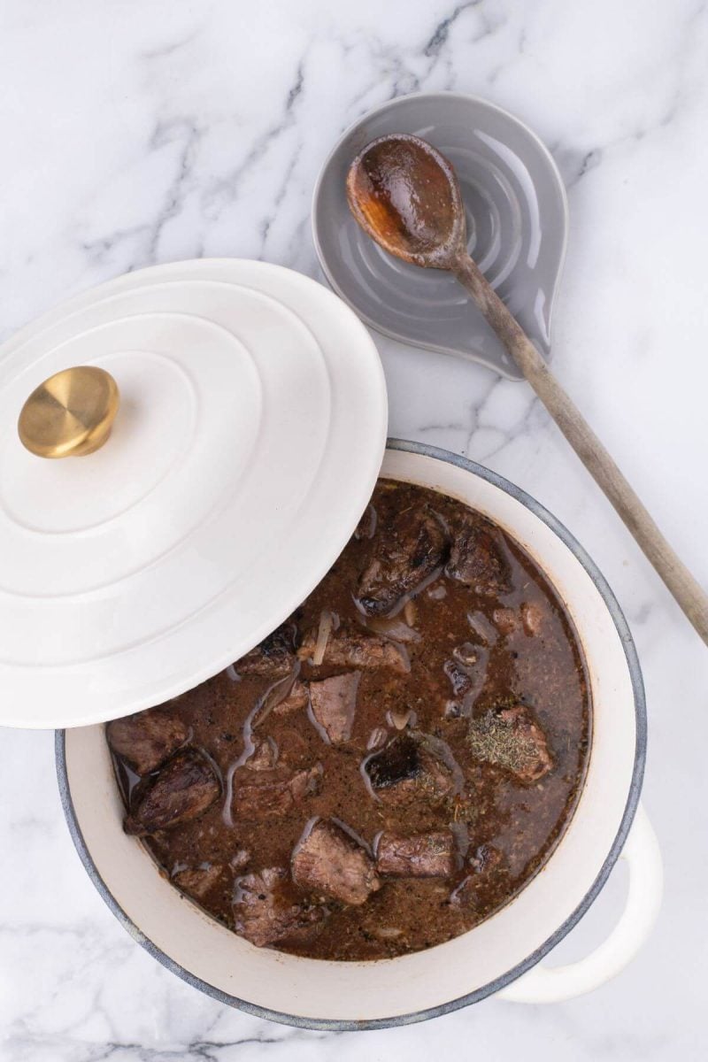 A lid starts to cover the pan of meat and sauce.