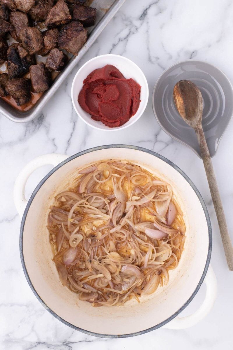 Shallots cook in a pot with broth.