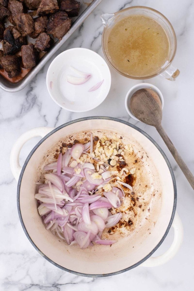 A pot holds shallot slices and is next to other ingredients.