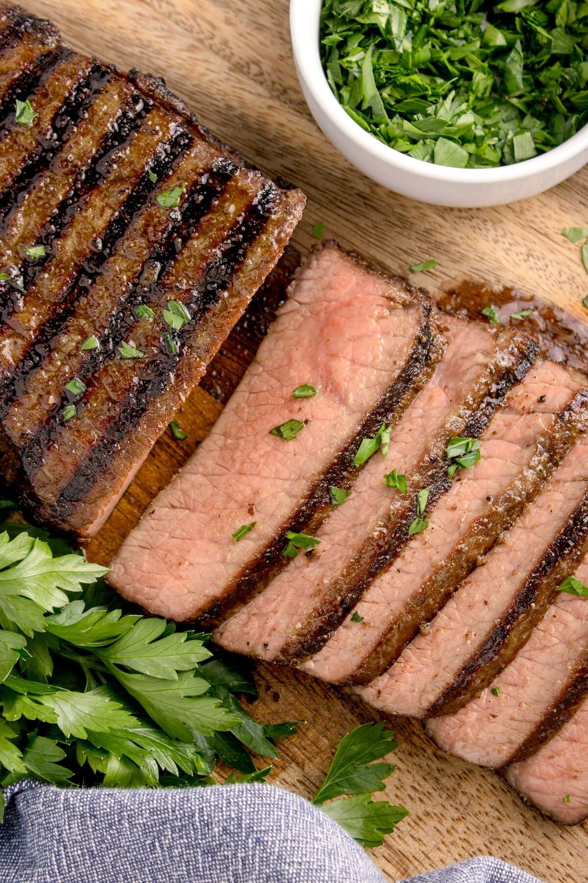 A cutting board is filled with steak slices and greens.