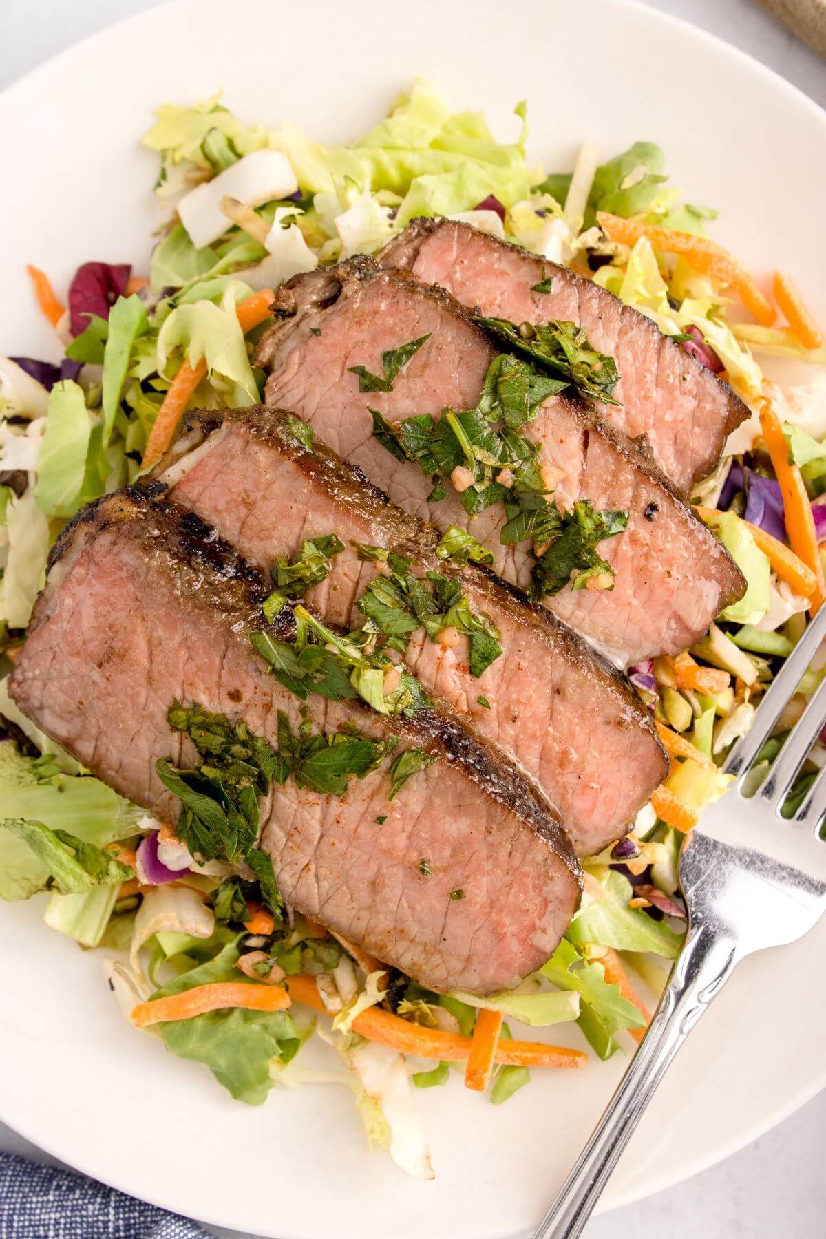 Meat slices are centered on plate over salad.