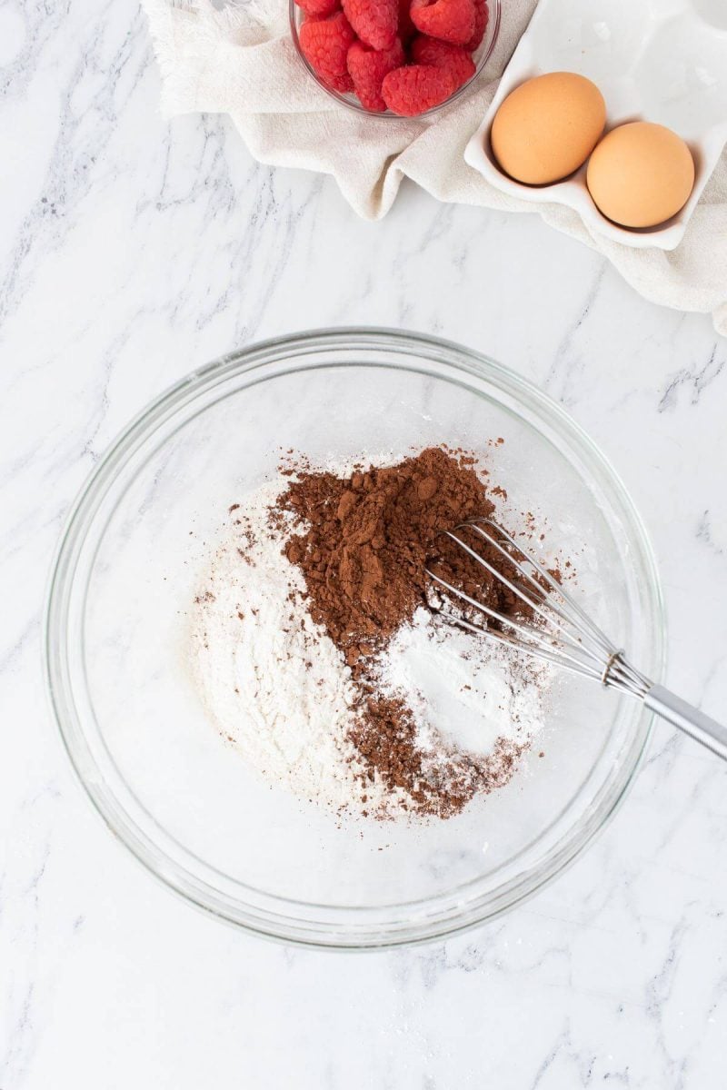 Cocoa powder and white dry ingredients are in a bowl with a whisk at the ready.