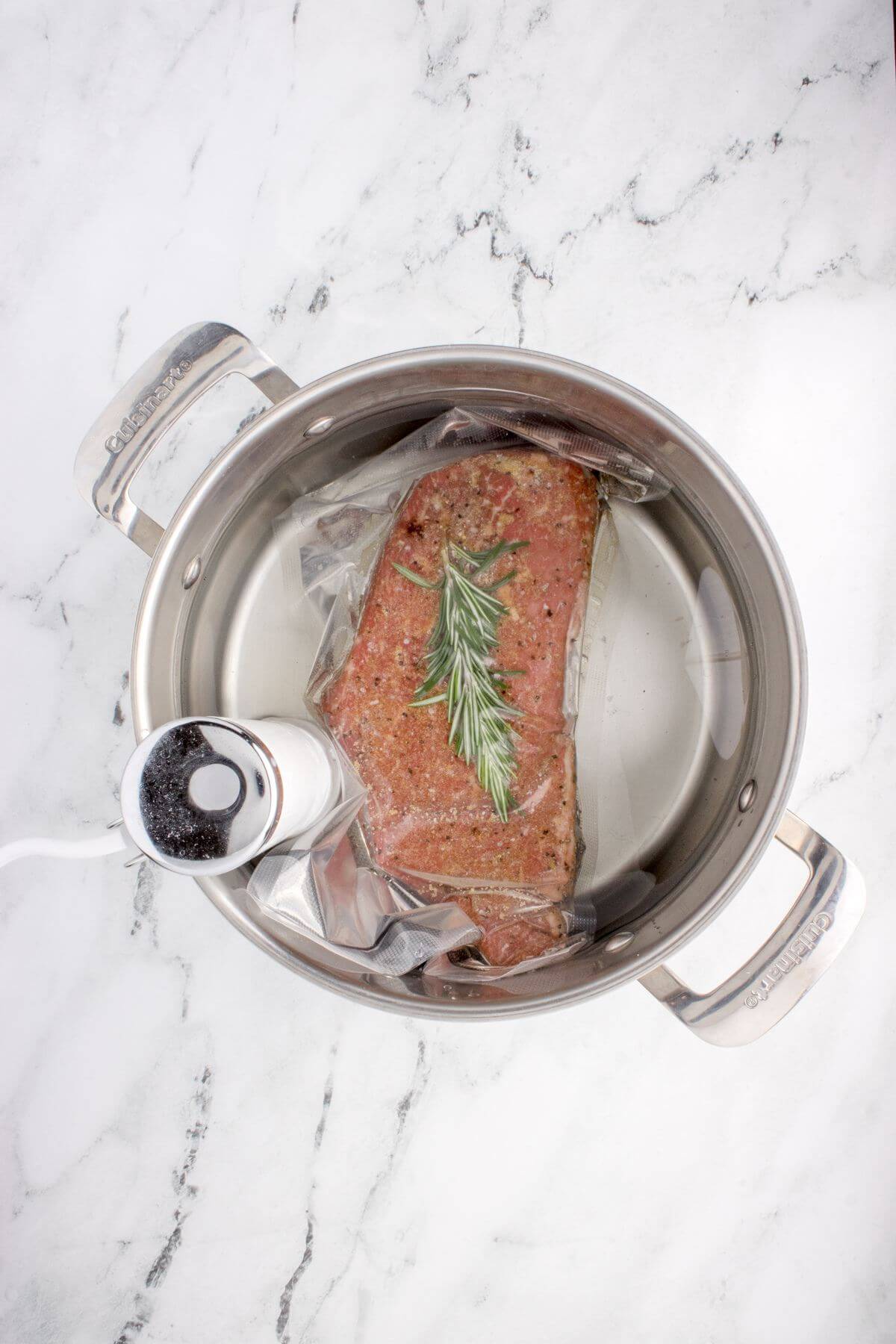 Plastic bag with meat is in a sous vide cooker.