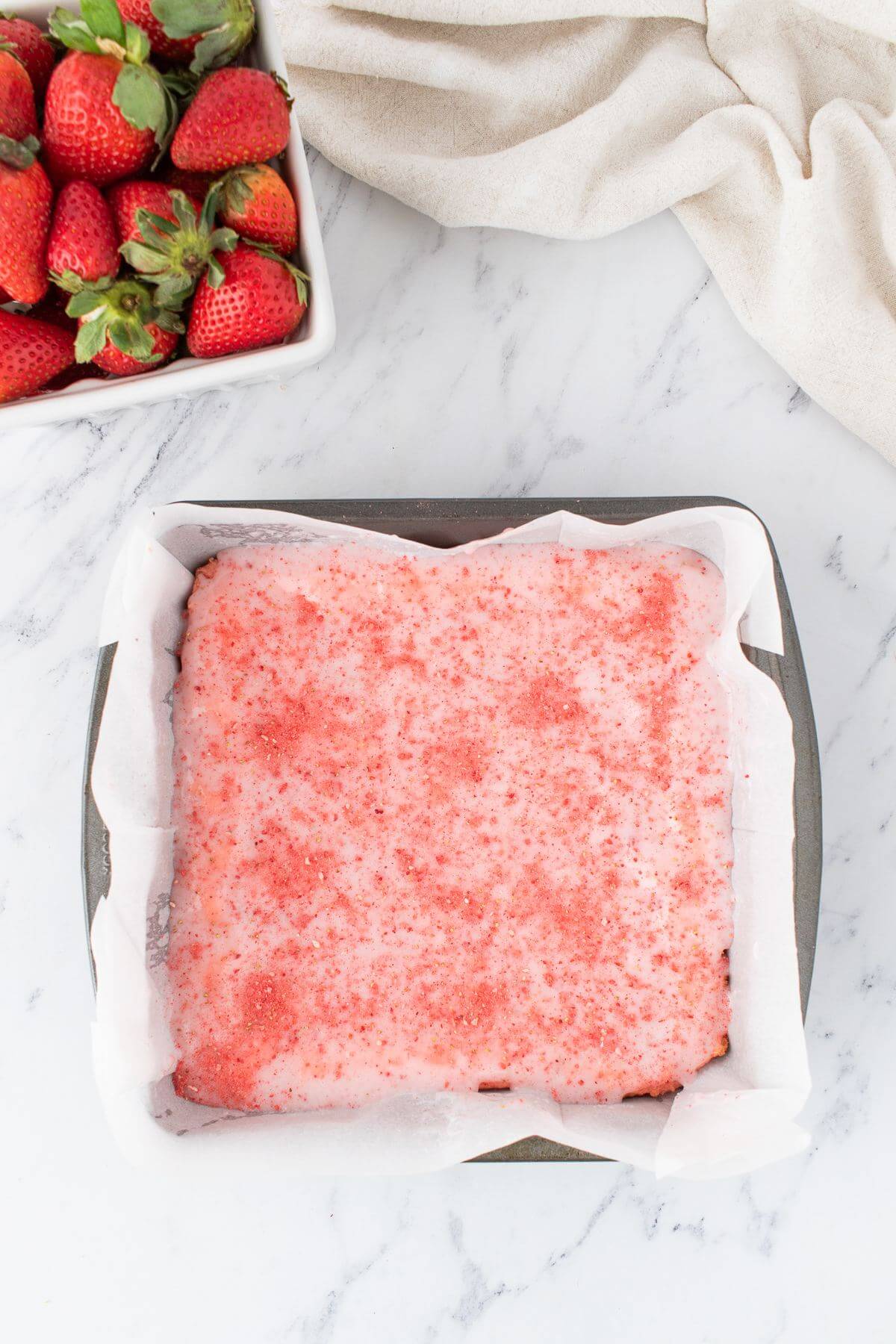 A pink cake is topped with more pink powder in a cake pan.