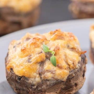 A close up view shows layers of melted cheese on top of stuffed mushroom.