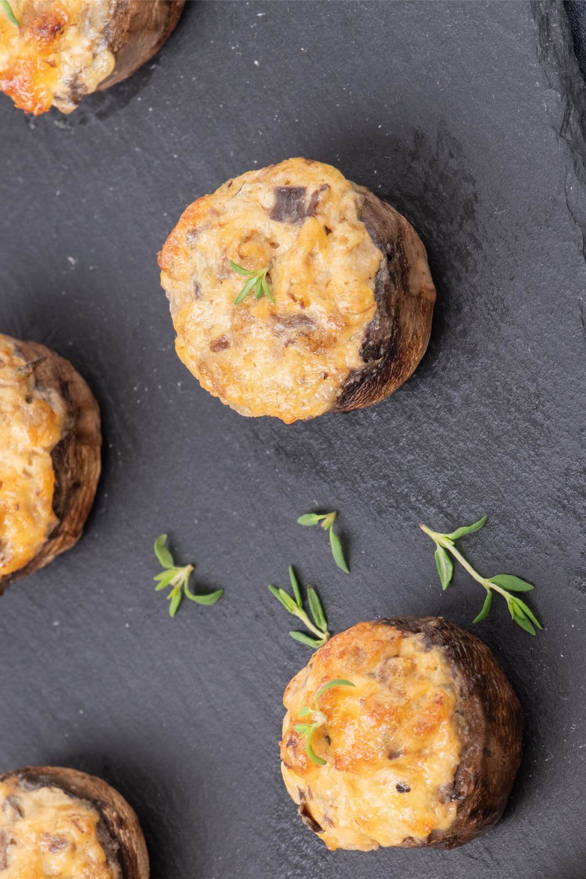 Five stuffed mushrooms are decorated with garnish.