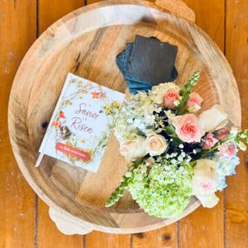 Spring flowers on round wooden tray with Easter Devotional book and coasters.