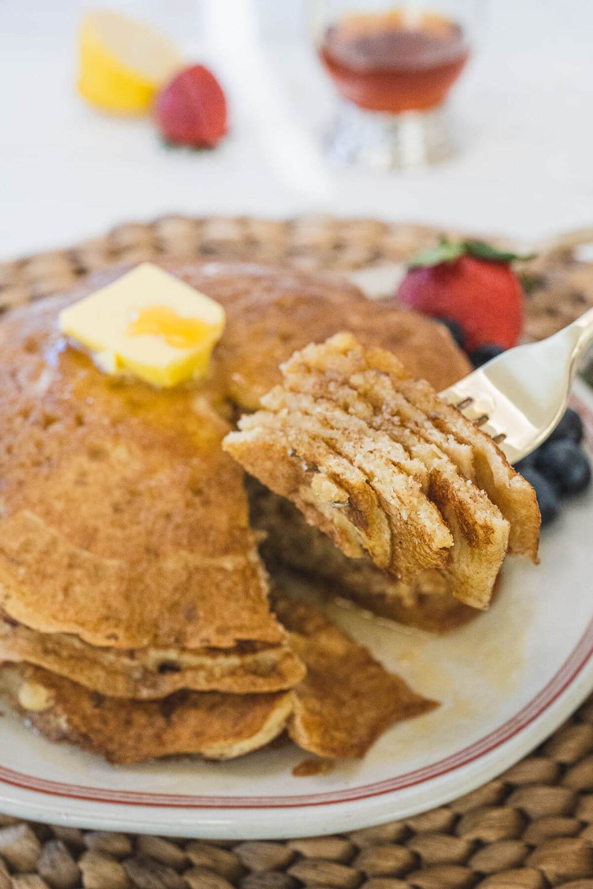 A fork holds up a bite of pancake layers ready to eat.