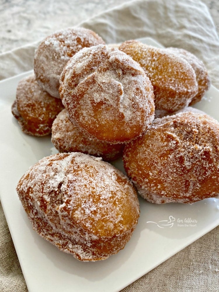 Paczki Polish donuts dusted with sugar on a plate.