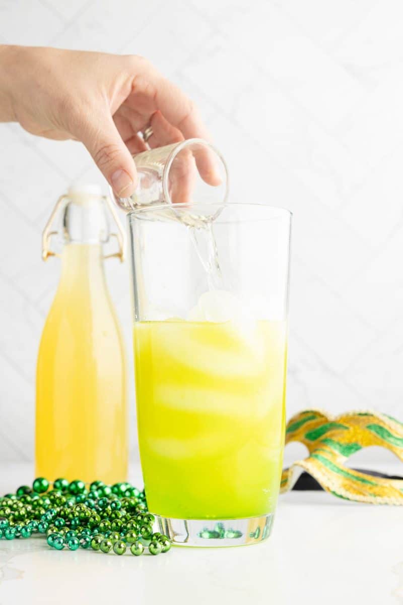 Hand pouring vodka into shaker glass for Hand Grenade drink. 