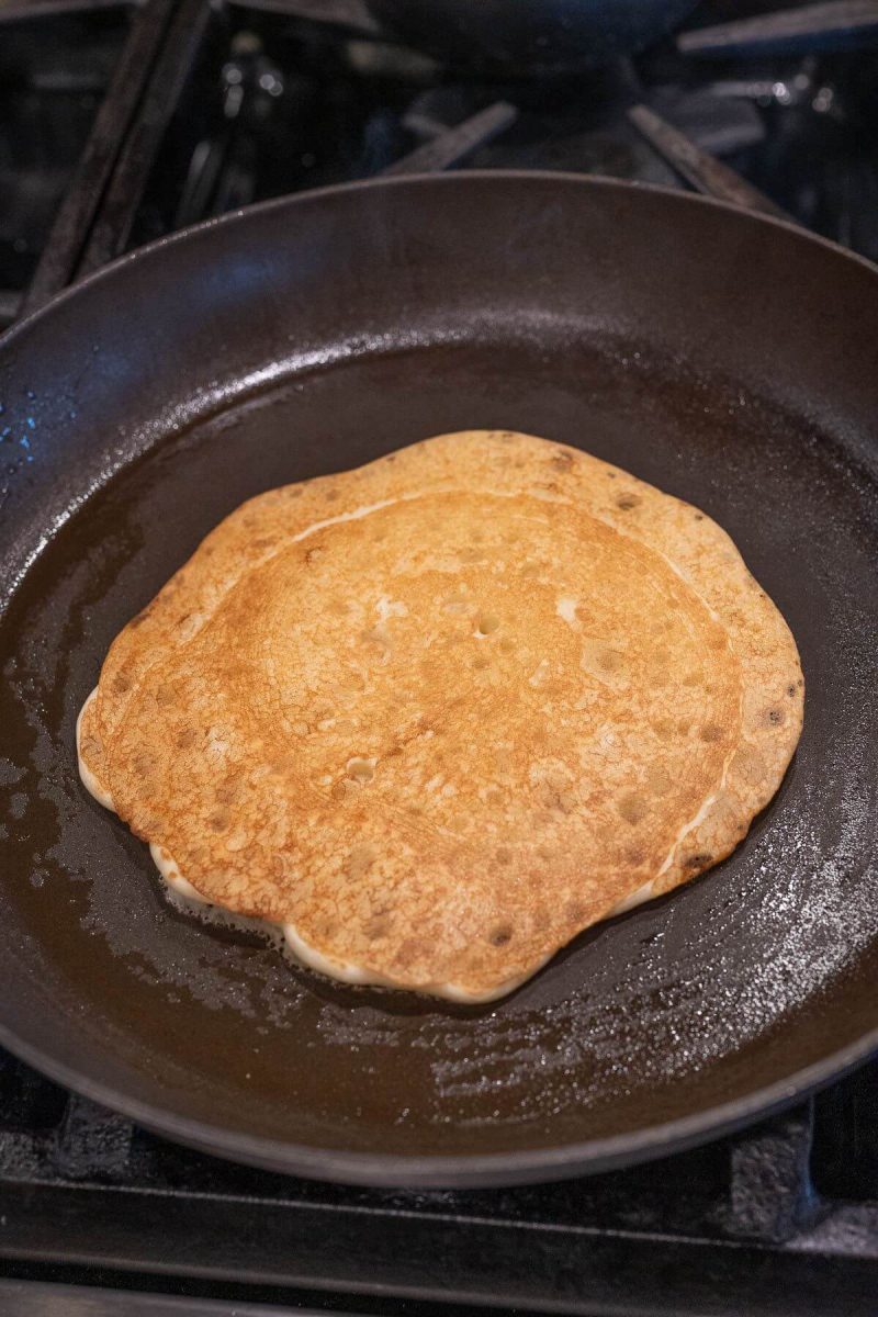 A golden brown pancake sits in a cast iron skillet.