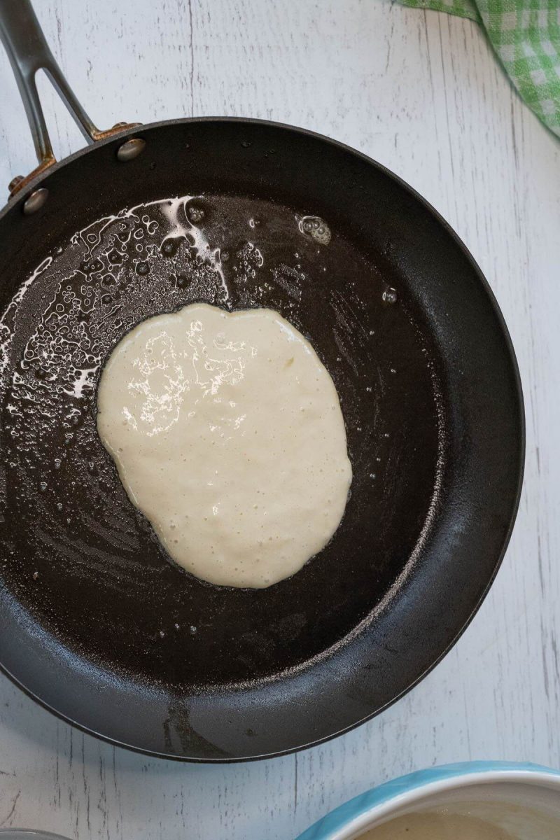 A blob of pancake batter sits in a greased cast iron skillet.