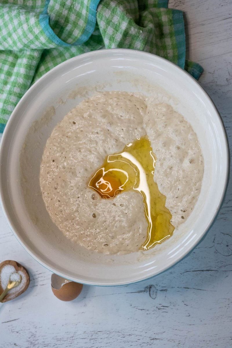 An egg was cracked into a bowl with a sourdough sponge.