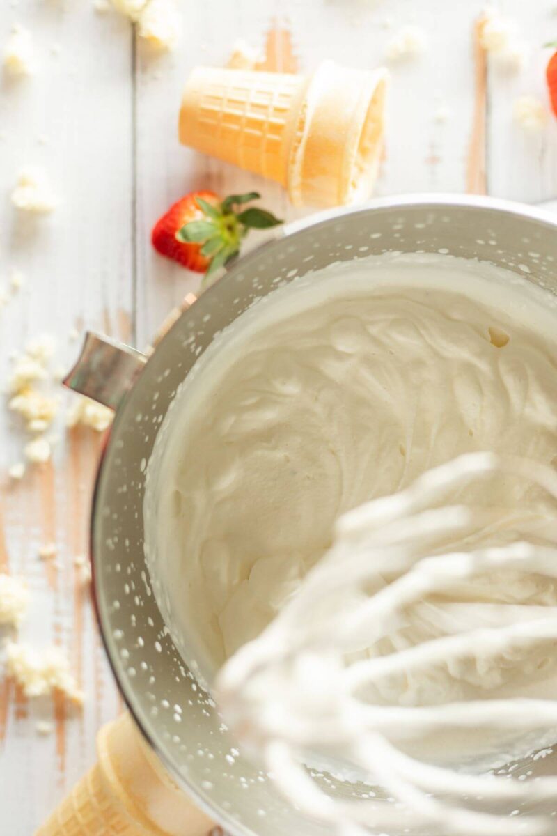 A stand mixer bowl has whipped topping inside.