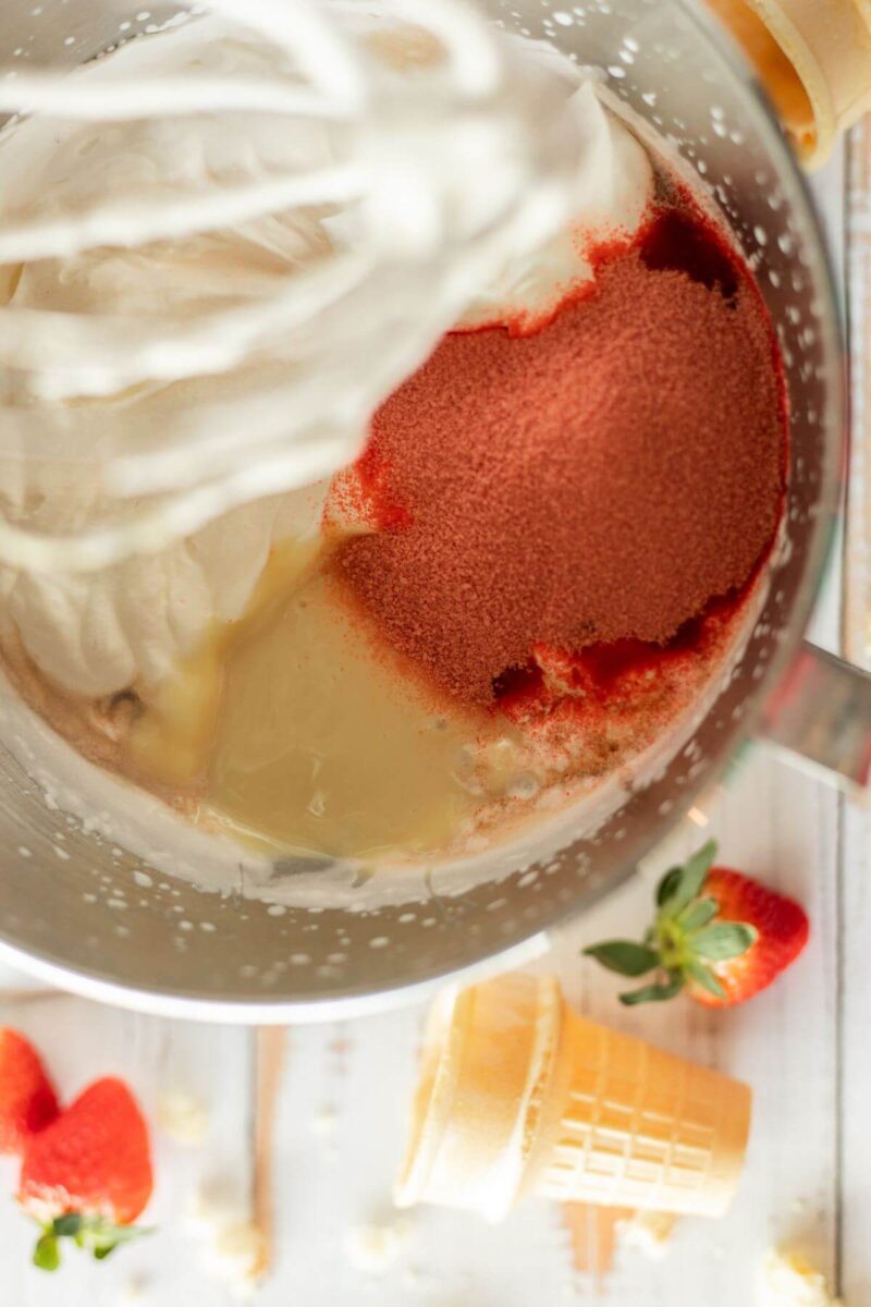 Strawberry jello powder, condensed milk, and vanilla in bowl of stand mixer. 