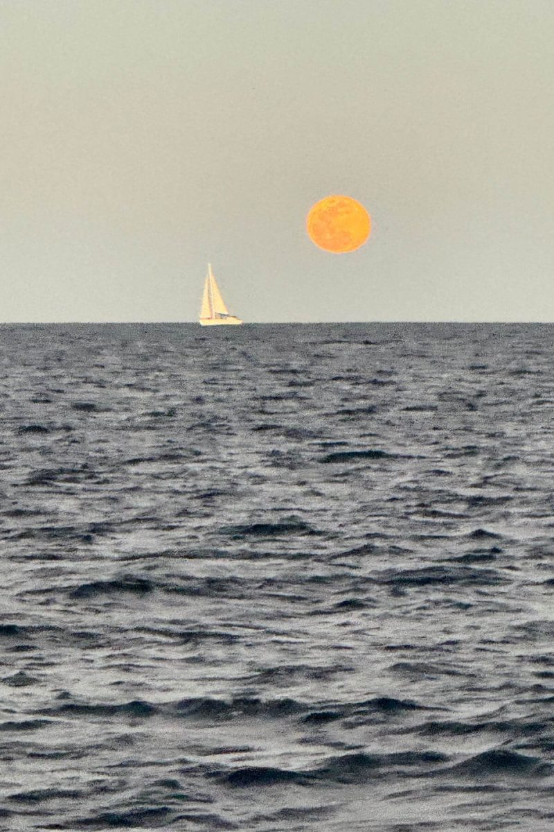 Moonrise on ocean with sailboat. 