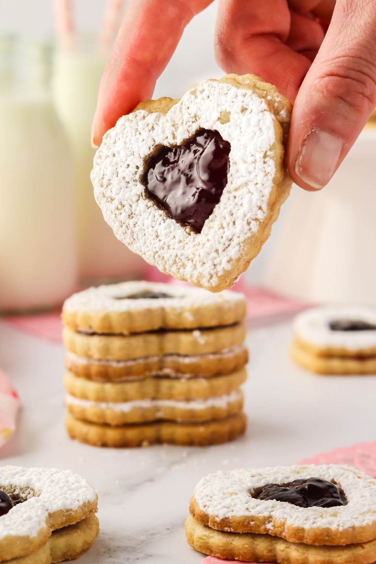 A hand holds up a heart cookie to show.