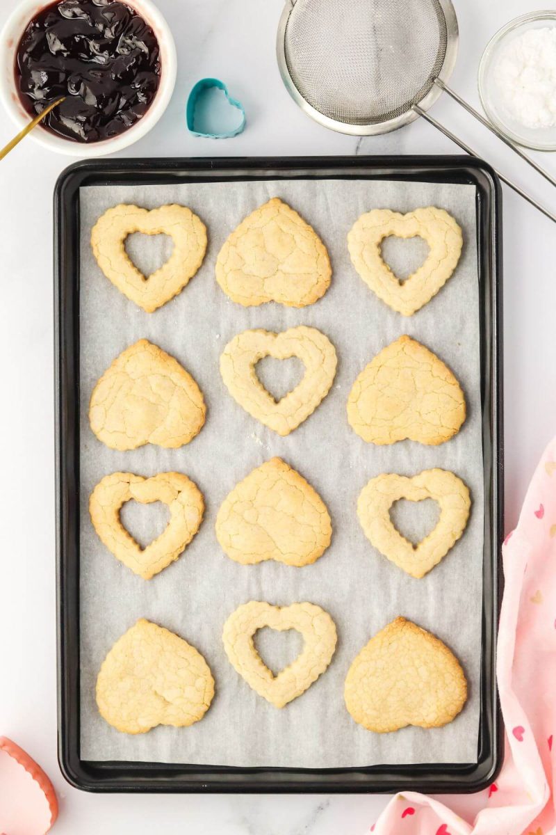 Light cookie shapes are on paper on cookie sheet.