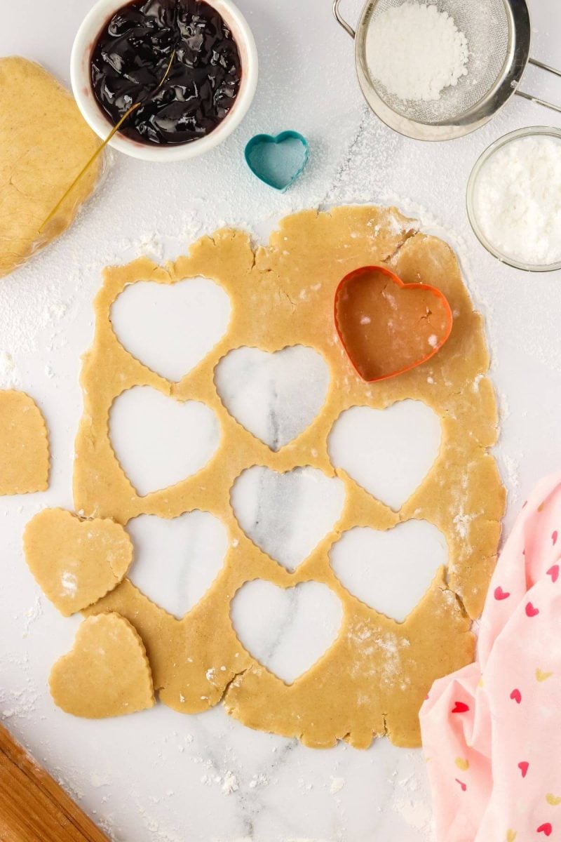 A heart shaped cookie cutter cuts out cookies.