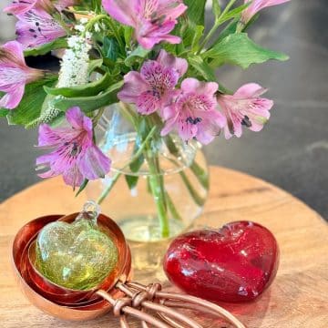 Valentine's day vignette with glass hearts, copper measuring cups and flowers.