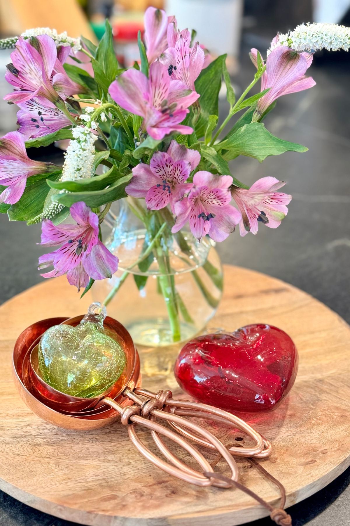 Valentine's day vignette with glass hearts, copper measuring cups and flowers.
