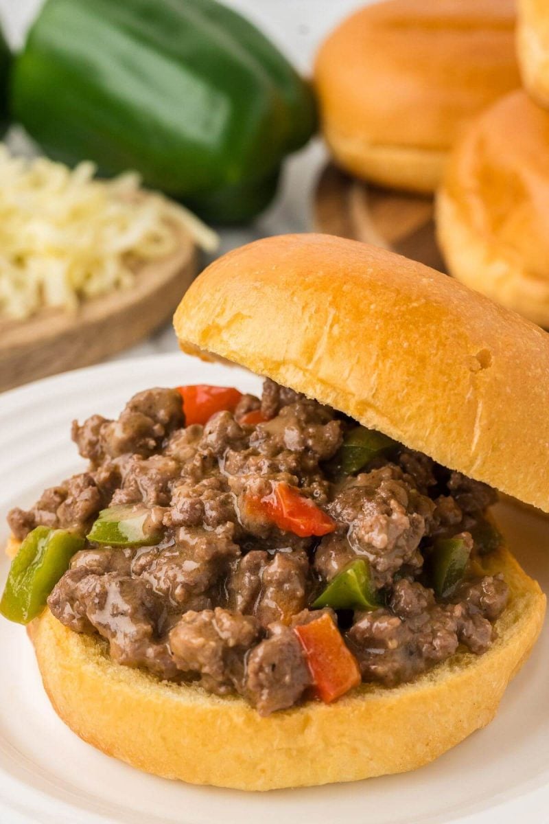 A ground beef Philly cheesesteak sandwich has most of its meaty filling visible as the top bun is propped backward.