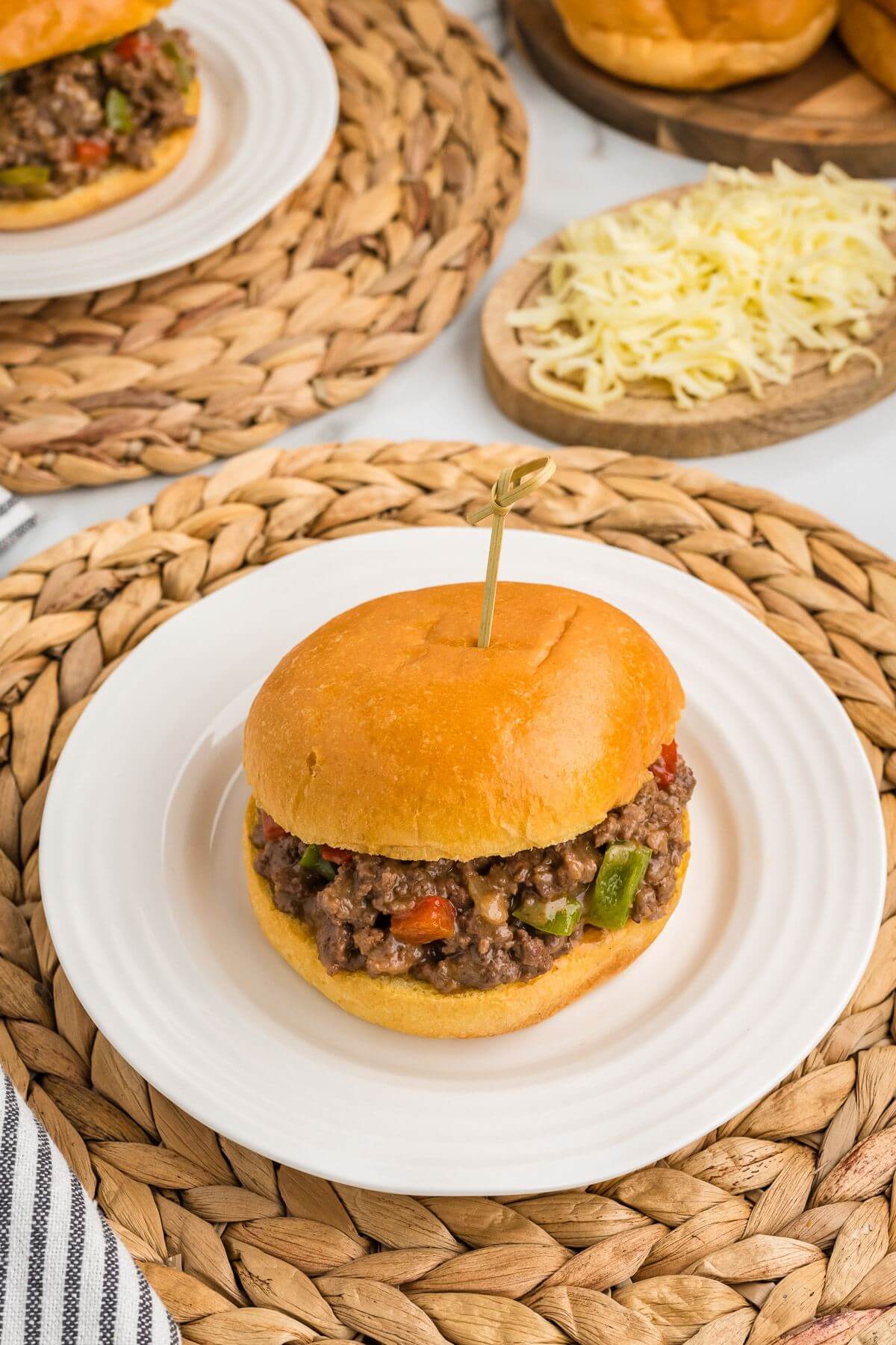 Sandwiches are on a set table with a plate of extra shredded cheese.