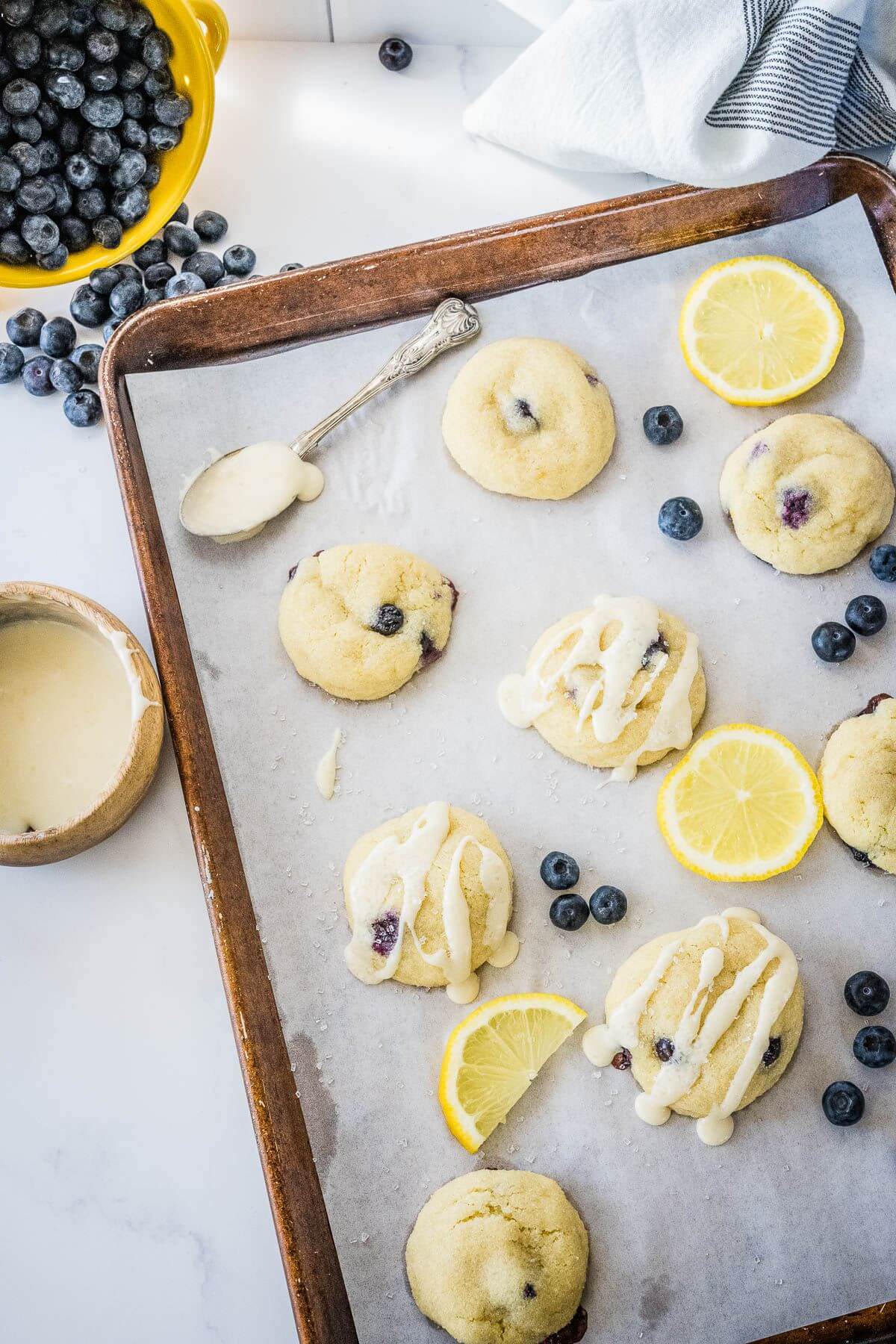 Lemon blueberry cookies on baking sheet with lemon glaze. 