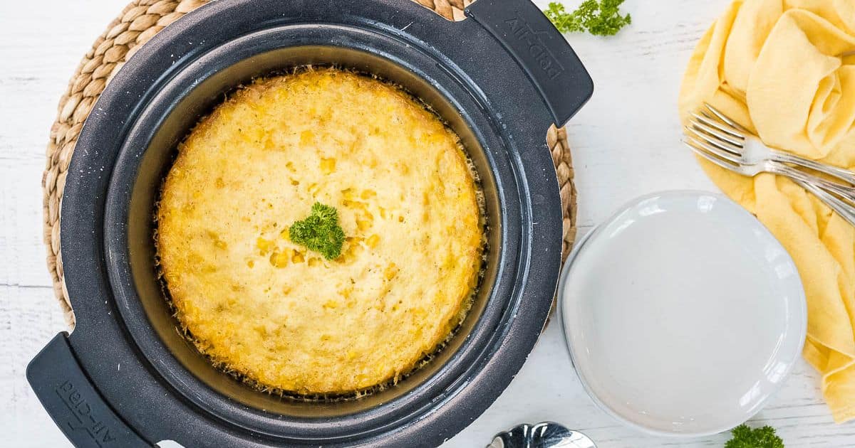 Crock pot corn casserole baked in a round crockpot, golden and hot. 
