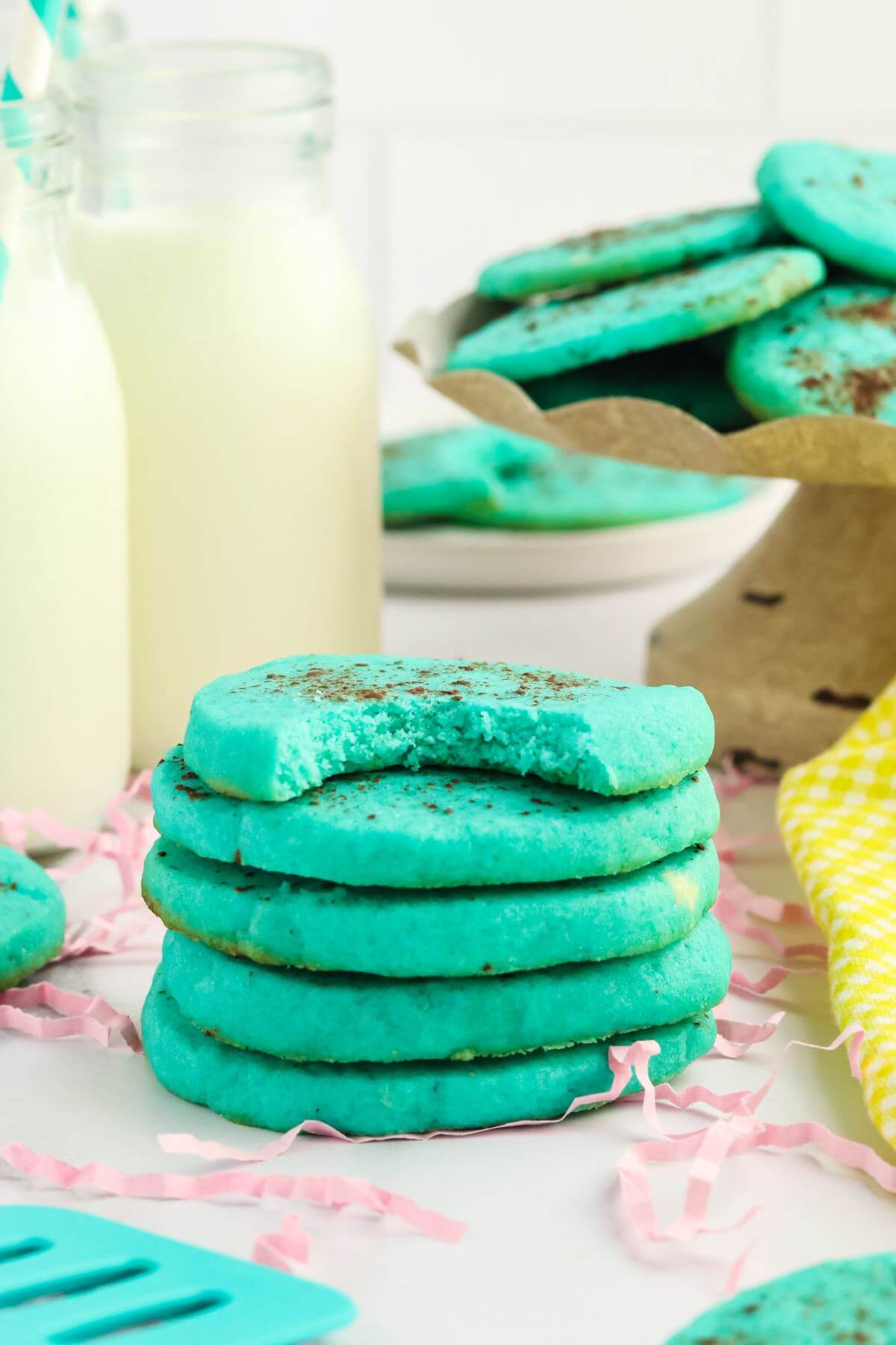 Robins egg cookies stacked with jar of milk behind.