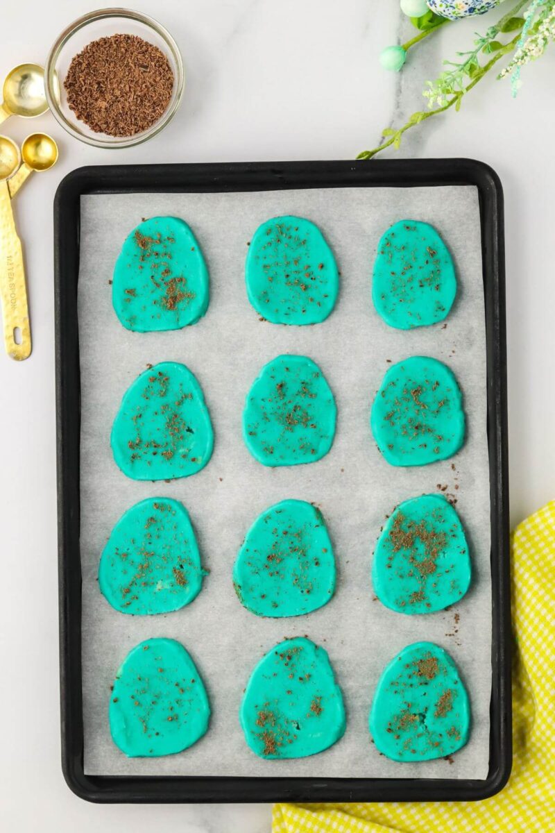 Sliced blue Robin's eggs sprinkled with shaved chocolate on baking sheet.