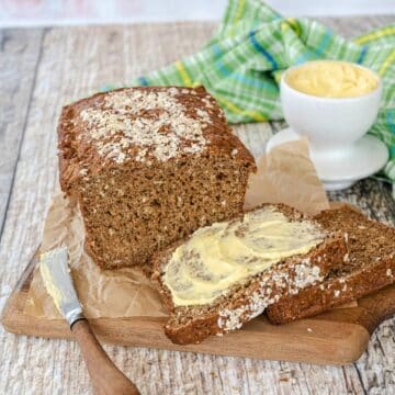 Guinness Irish brown bread on cutting board with slices smeared with Irish butter.