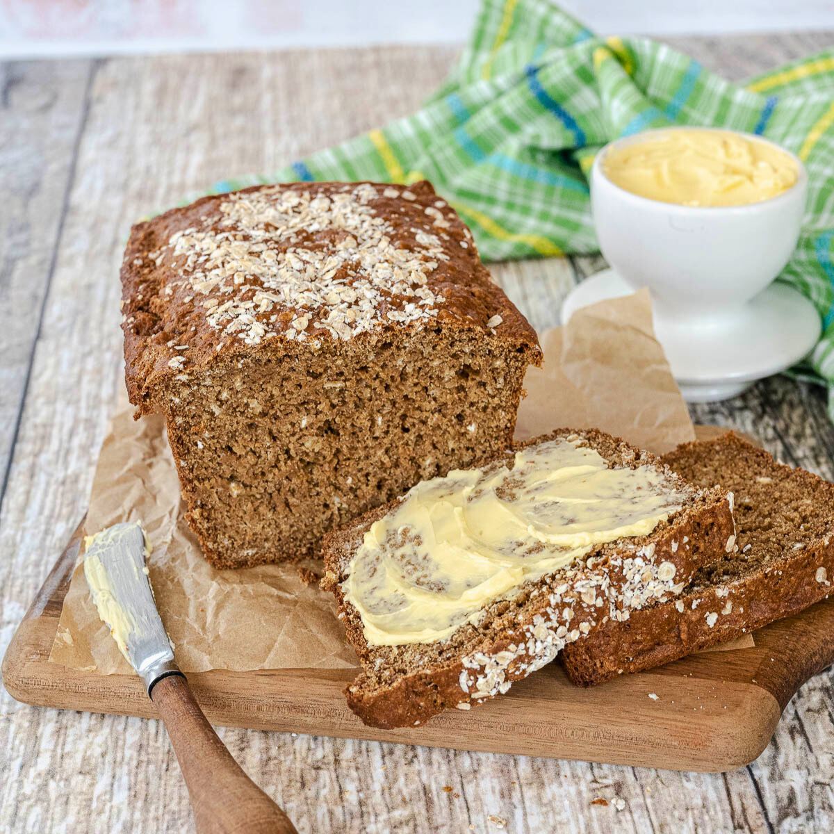 Guinness Irish brown bread on cutting board with slices smeared with Irish butter.