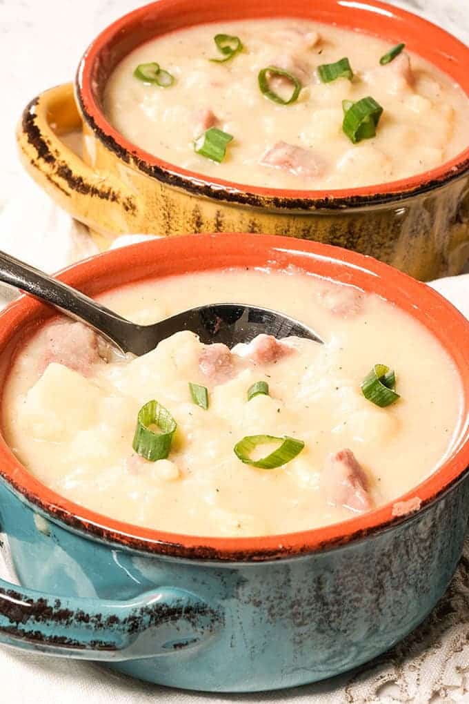 Ham and potato soup in serving bowls with spoon.