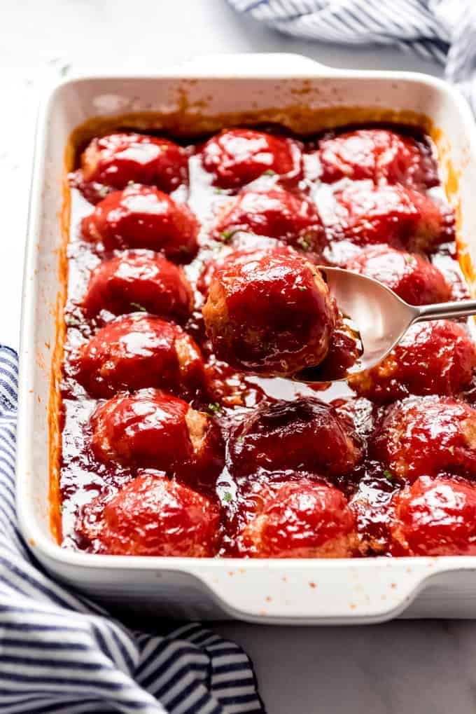 A casserole dish full of Iowa ham balls with a sticky sauce over the top.