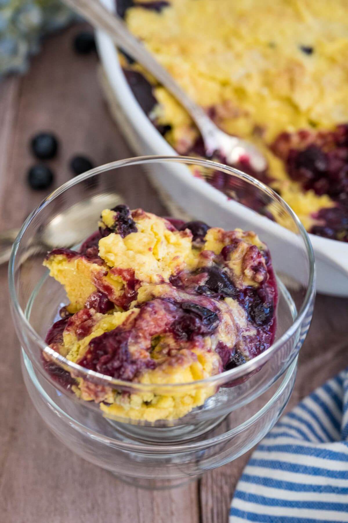 Purple blueberry swirl mixed in a yellow cake sits in bowl next to full pan.