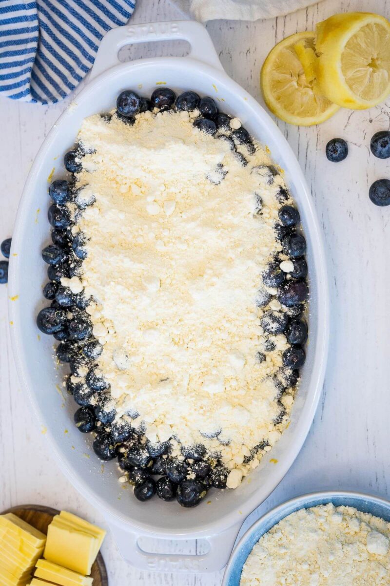 A thick layer of cake mix covers blueberries in a baking dish.
