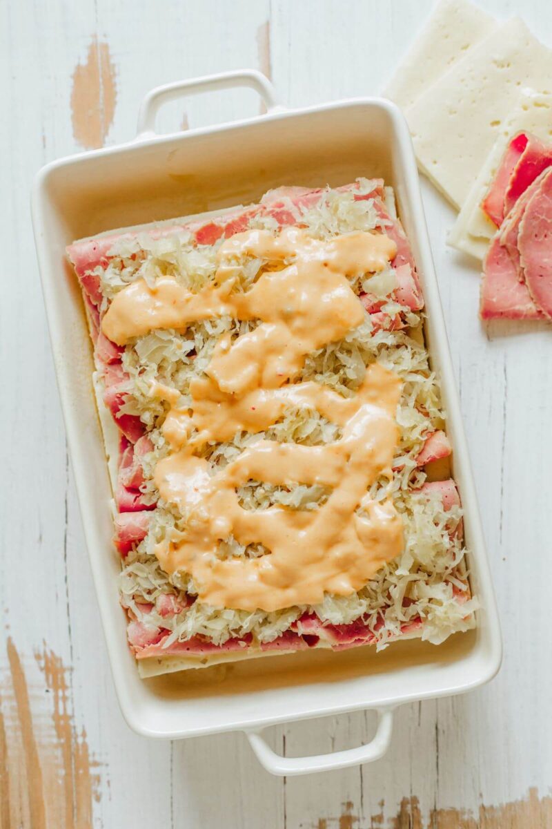 Thousand Island dressing is poured over the saurkraut and meaty layers in dish.
