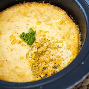Corn casserole made in crockpot with serving removed to reveal, tender souffle like corn pudding casserole.