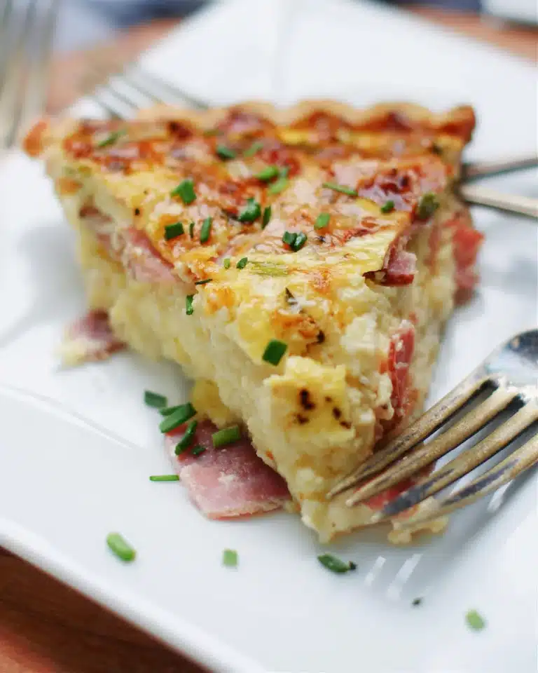 Ham and swiss quiche with a fork on a plate.