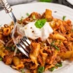 A serving of hamburger helper lasagna on a plate with a fork taking a bite.