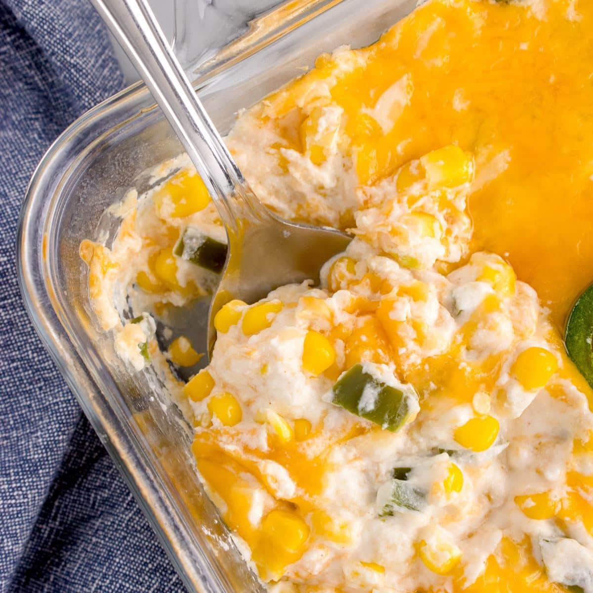 Jalapeno corn casserole in dish with spoon lifting a creamy cheesy bite.