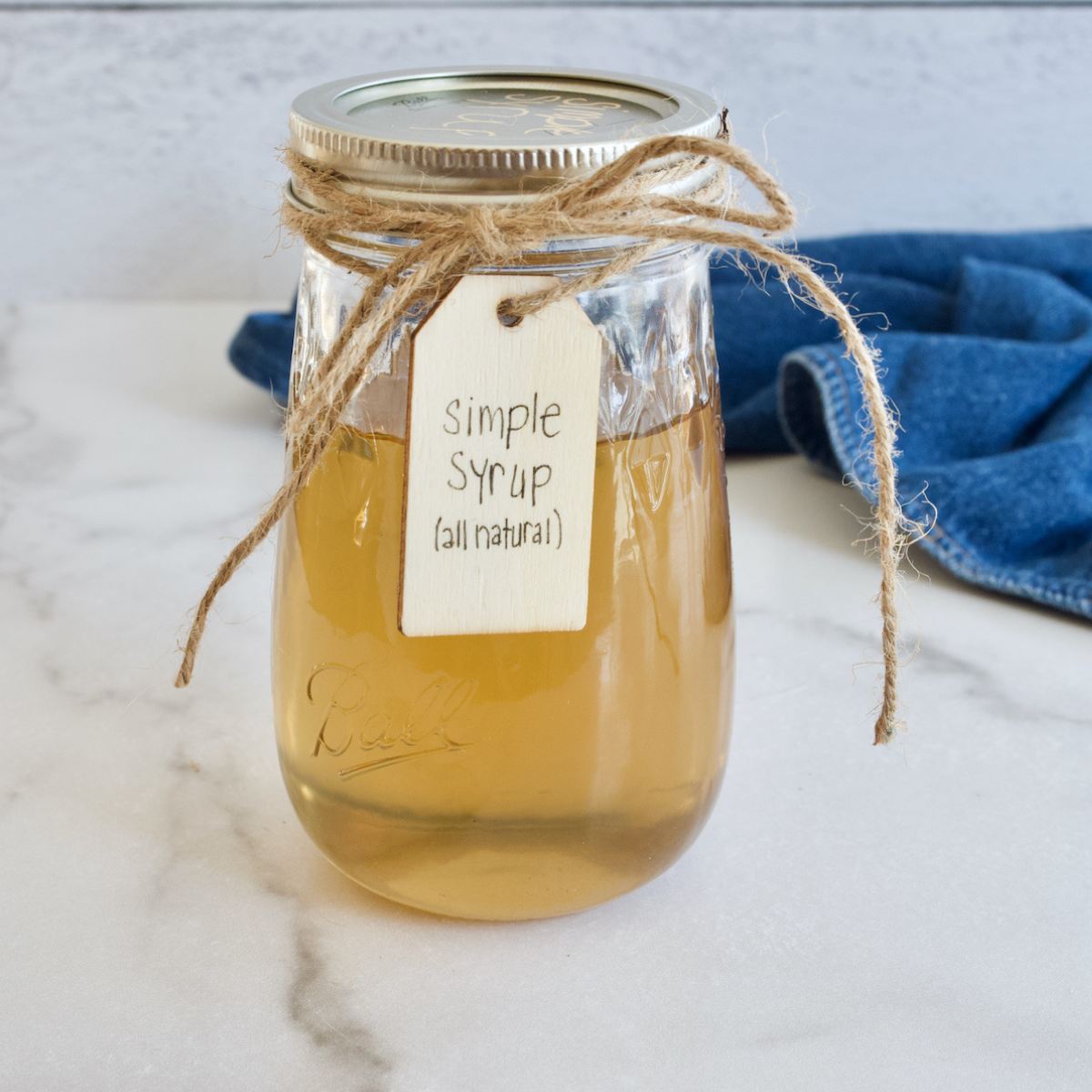 Jar of golden liquid, Liquid cane sugar simple syrup tied with bow with a name tag.