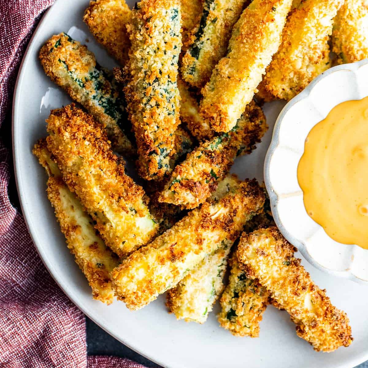 Air Fryer Zucchini fries on a plate with a dipping sauce.