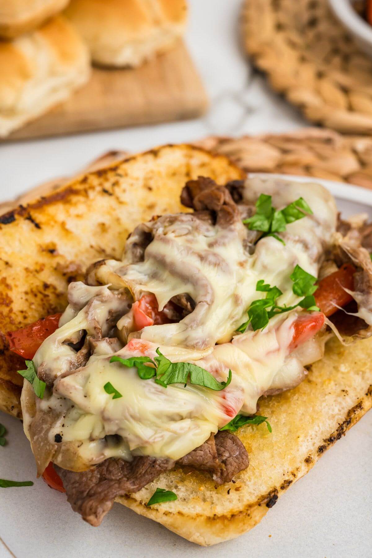 A toasted Hoagie roll holds layers of steak, gooey white cheese, and veggies.