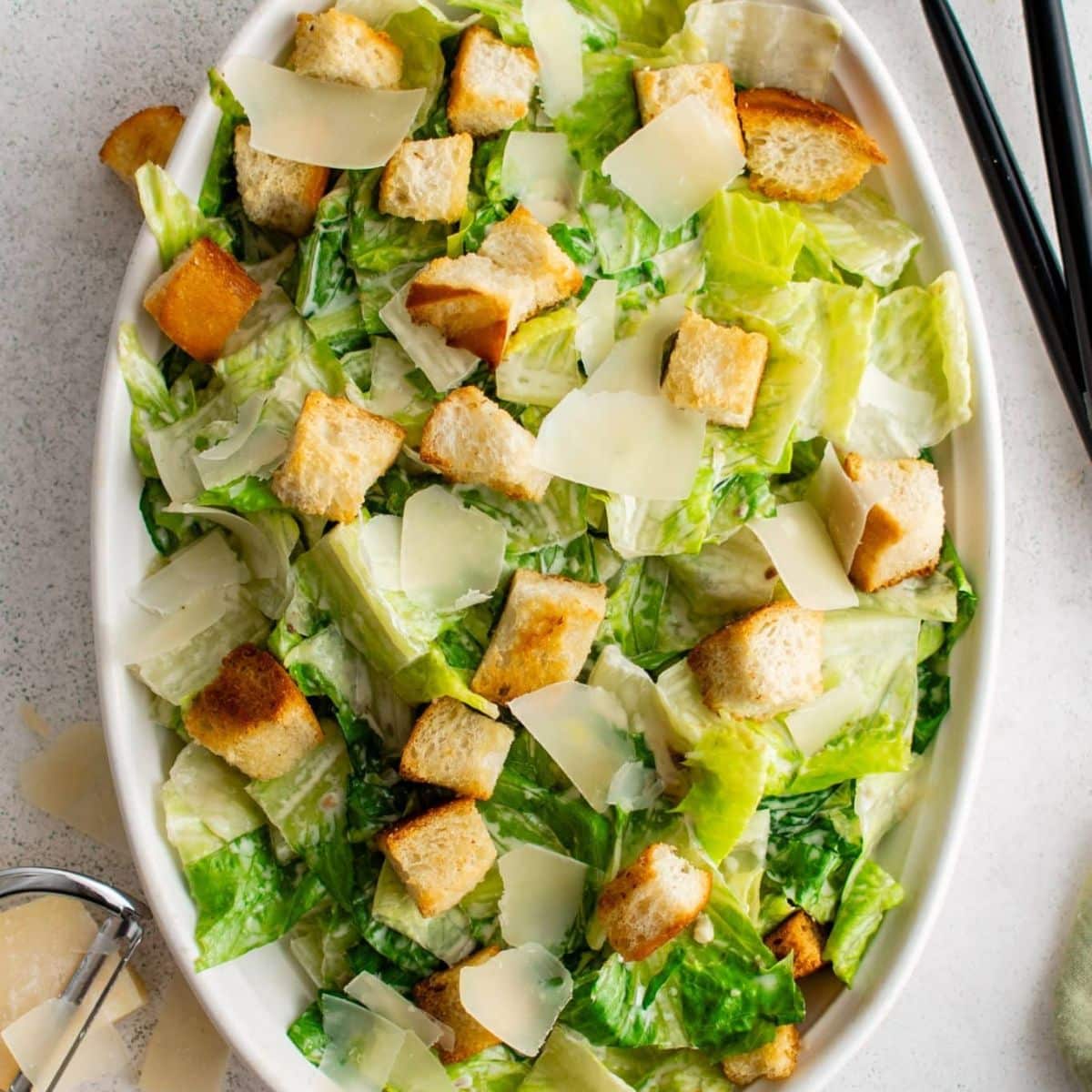 Caesar salad with croutons and shaved parmesan on a platter.