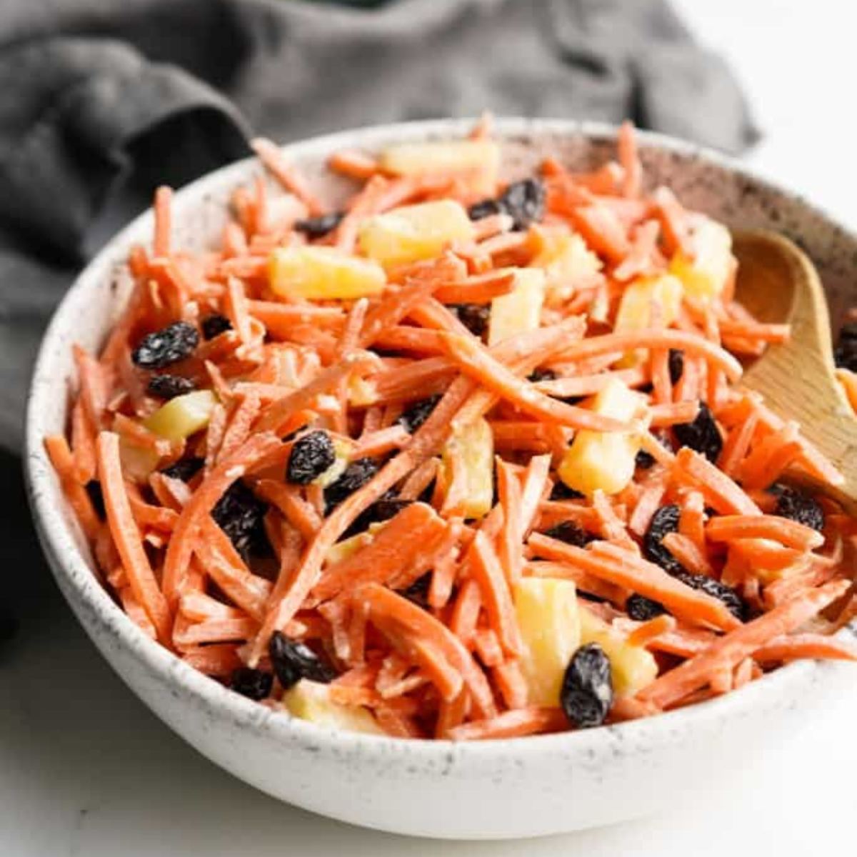Carrot and raisin salad in a pretty white serving bowl.