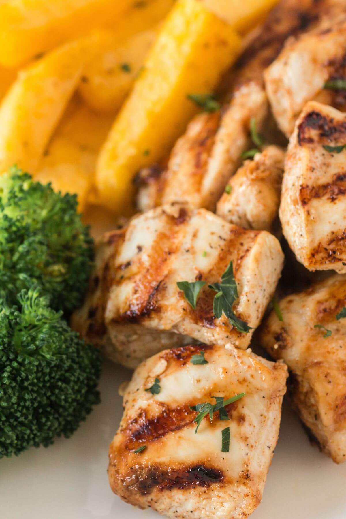 Yellow fries and green broccoli lay next to chunky grilled nuggets.