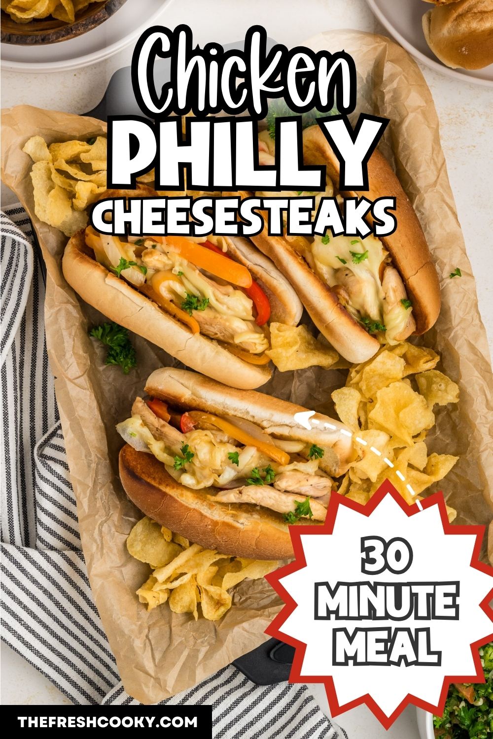 A tray filled with three philly chicken cheesesteaks with potato chips, to pin.